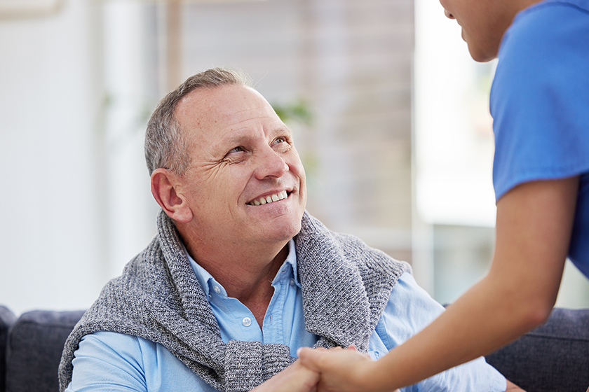 A senior man sitting in the clinic while his nurse helps him. 